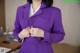 A woman in a purple suit is adjusting her tie.