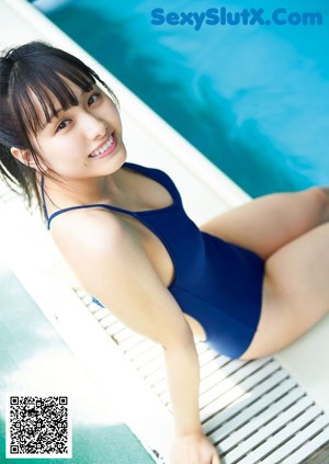A woman in a blue bathing suit sitting by a pool.