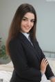 A woman in a business suit posing on a bed.