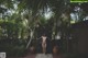 A naked woman standing in the middle of a garden.