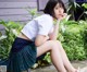 A woman in a school uniform sitting on a bench.