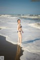 A woman in a bikini standing on the beach.