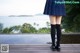 A woman in a blue skirt and black stockings standing on a wooden deck.