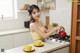 A woman in a yellow top is preparing food in a kitchen.